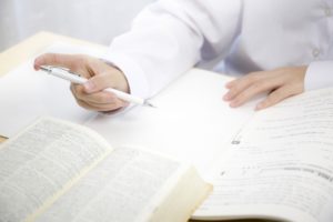 辞書を見ながらペンとノートで勉強する女性